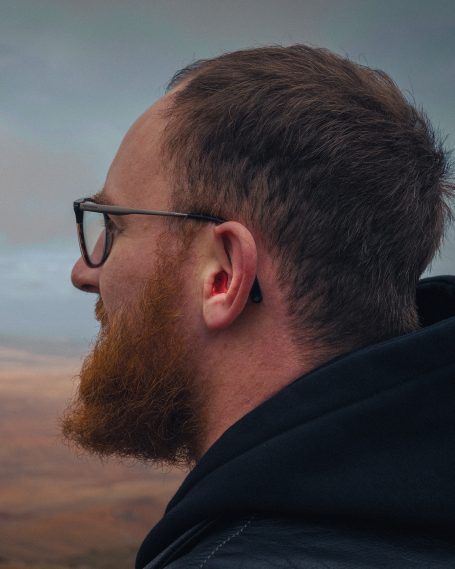 Seitliche Ansicht eines Bikers mit sicher sitzendem rotem Gehörschutz zur Demonstration der anatomischen Passform und Helmkompatibilität.