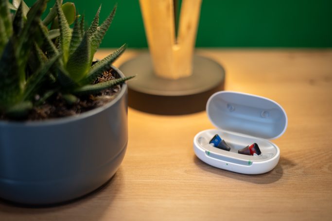 Mobiles weißes Ladecase für Signia Silk IX, geöffnet auf einer Holzoberfläche in modernem Lifestyle-Ambiente.