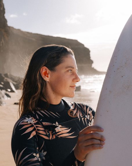 Surferin mit maßgefertigtem Hörluchs Gehörschutz zum Schutz vor Kaltwasser und Wind.