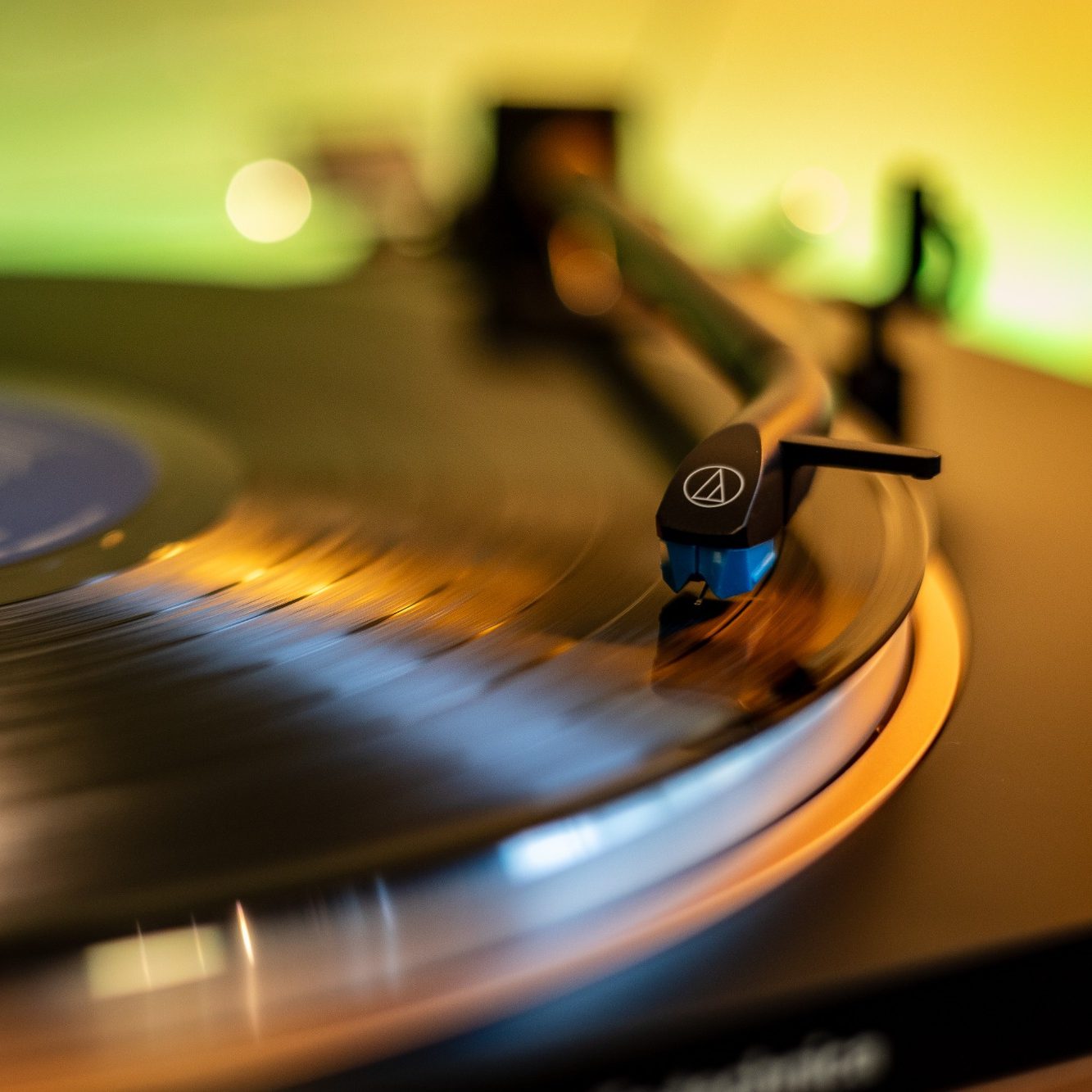Schallplatte auf einem Plattenspieler mit schöner Beleuchtung im Hintergrund.
