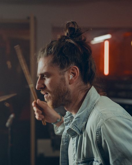 Ein Schlagzeuger bei der Performance mit diskret eingesetztem professionellem Gehörschutz für optimalen Sound und Schutz.